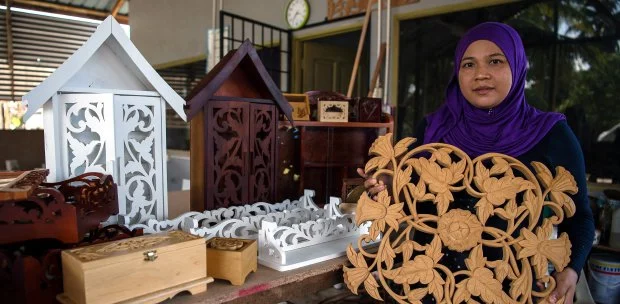 Ruwaida Baharudin, a woman woodcarver working on a wooden sculpture